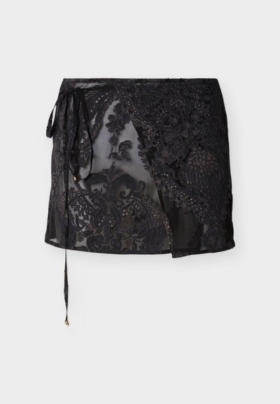 Μαύρη διαφανής μίνι φούστα με λουλουδάτα δαντελένια σχέδια και φιόγκο στο πλάι με μακριές κρεμαστές κορδέλες.