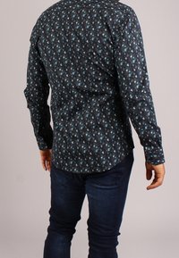 Camicetta nera con bottoni, con motivo floreale in verde acqua e azzurro chiaro, maniche lunghe, orlo curvo e silhouette aderente.