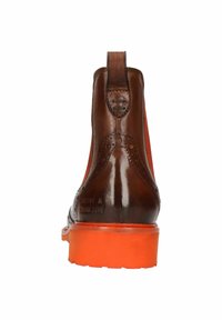 Botín de cuero marrón hasta el tobillo con detalles de brogue y una lengüeta. Presenta una suela de goma naranja y un acabado suave y brillante.