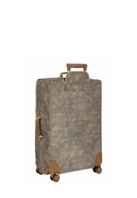 Valise en tissu tissé de couleur beige et marron, avec une poignée rétractable, des accents marron et quatre roues pour la mobilité. Fermeture à glissière sur le dessus.