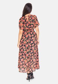 Abito maxi floreale con sfondo nero, caratterizzato da rose rosse e verdi, maniche corte, vita elastica e un piccolo dettaglio a forma di chiave sulla schiena.