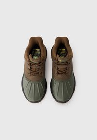 Zapatillas impermeables de color marrón y verde con suela de goma estriada, cuello acolchado y diseño con cordones. Incluye un logo en la lengua.