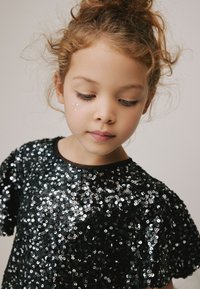 Schwarzes Paillettenoberteil mit kurzen Ärmeln, einem abgerundeten Ausschnitt und einer glänzenden Textur. Verziert mit kleinen funkelnden Details auf der Vorderseite.