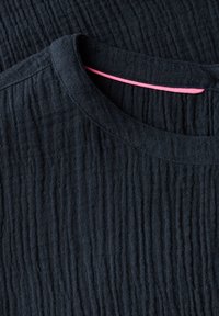 Dunkelblaues, strukturiertes T-Shirt mit vertikalen, gerippten Mustern und Rundhalsausschnitt. Ein pinkfarbener Akzent ist am Ausschnitt sichtbar.