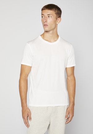 White short-sleeve t-shirt with round neck, lightweight fabric, smooth texture, and plain design, worn with gray sweatpants.