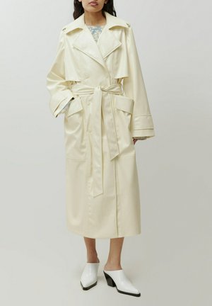 Crèmekleurige, faux leren trenchcoat met een ceintuur in de taille, grote kraag en zakken. Kenmerkt zich door een knielange ontwerp en een relaxed fit.