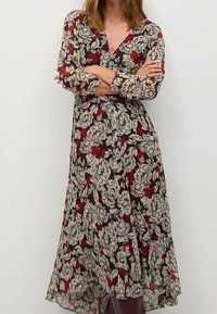 Długa, przejrzysta sukienka z kwiatowym wzorem w bieli i czerwieni na ciemnym tle, z długimi rękawami i dekoltem w kształcie litery V.