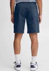 Námořnicky modré cargo šortky s volnějším střihem, vybavené bočními a zadními kapsami. Vyrobené z hladké látky, s elastickým pasem pro pohodlí.