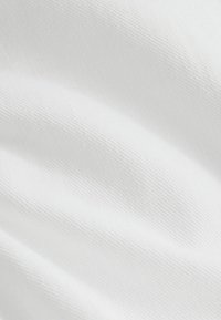 Nærbillede af glat hvidt stof med fin diagonal vævning og bløde folder, der skaber blide skygger.