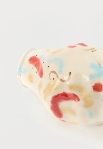 Μικρή κεραμική κουμπαράς με χειροποίητες κόκκινες, μπλε και μπεζ αφηρημένες κηλίδες σε λευκό φόντο.