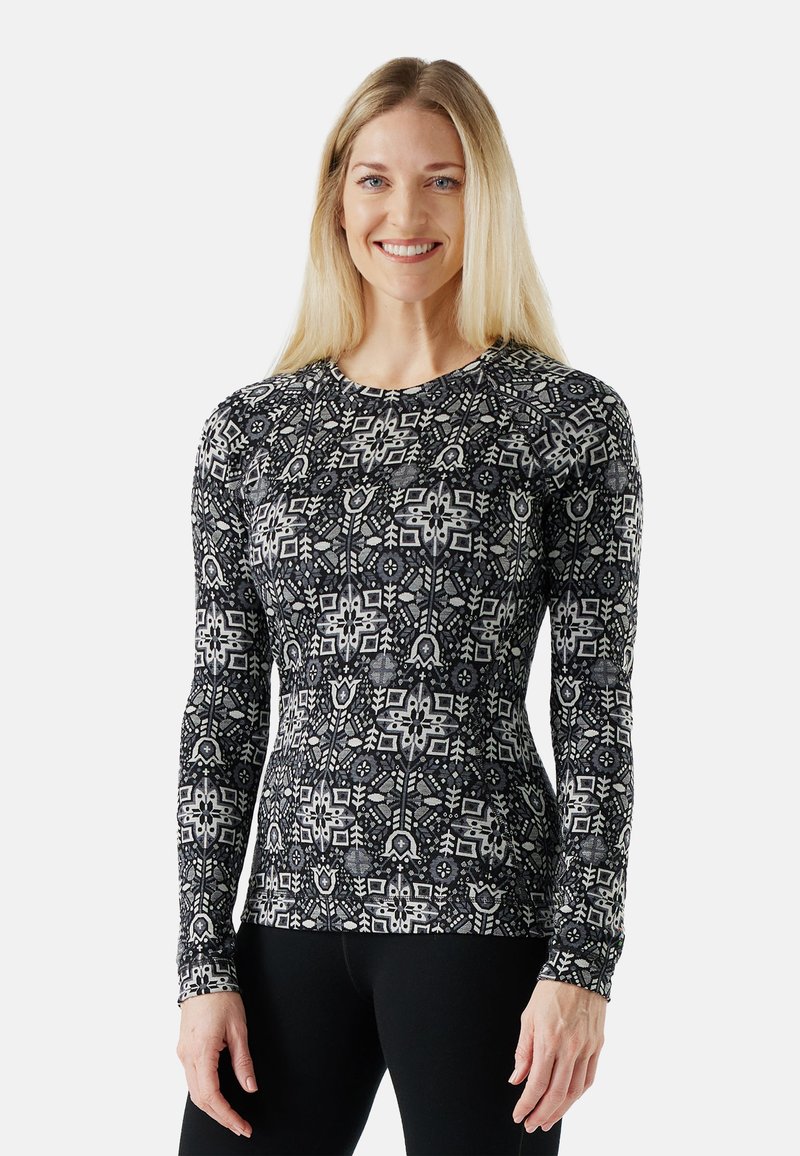 Long-sleeve shirt in a black and white geometric pattern, featuring a round neckline and fitted design. Made from a stretchy, breathable fabric.