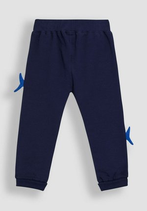 Navy blue jogger-housut, jotka on valmistettu puuvillasta. Niissä on sininen kalan muotoinen applikaatio sivulla, ribattu lahje ja joustava vyötärönauha.