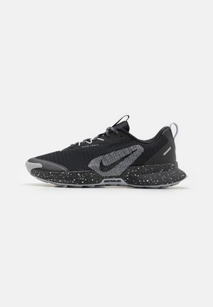Schwarzer und grauer Nike Trail Laufschuh mit gesprenkelter Sohle, strukturiertem Obermaterial und großem Nike-Swoosh an der Seite.
