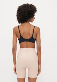 Μαύρο ασύρματο εσώρουχο με δαντελωτές άκρες και ρυθμιζόμενες τιράντες, συνδυασμένο με ουδέτερα ψηλόμεσα κολακευτικά σορτς, λεία υφή, χωρίς σχέδια.