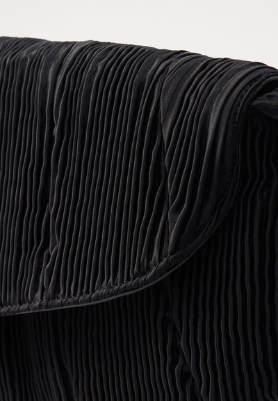 Tessuto nero con sottili pieghe verticali e bordi cuciti, che mostrano la texture e la cucitura dettagliata su una sezione a soffietto piegata.