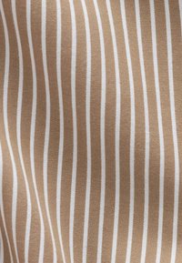 Tissu beige avec des rayures blanches verticales espacées régulièrement, créant un motif fluide et harmonieux.