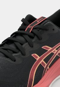 Chaussure de course noire avec un dessus texturé, des accents rouges et jaunes, des lacets et un logo. Dotée d'une semelle rembourrée et d'un profil épuré.