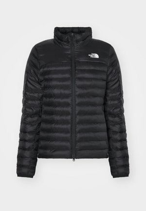 Zwarte pufferjack met een opstaande kraag, ritssluiting aan de voorkant en een gevoerd ontwerp. Bevat een logo op de linkerkant van de borst en elastische manchetten.