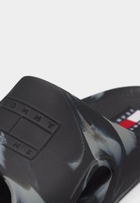 Μαύρο και γκρι μαρμάρινο σανδάλι με πλατφόρμα και φαρδιά λουρί με ανάγλυφο λογότυπο Tommy Jeans, καθώς και υφασμένο πέλμα με μικρή λεπτομέρεια σημαίας.