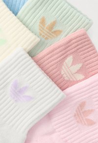Ribbed socks in pastel colors: light blue, mint green, cream, pink, and white, each with a contrasting logo pattern. Soft cotton material.