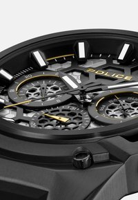 Orologio analogico nero con quadrante a motivo esagonale, accenti dorati, sottodial cronografici e indici delle ore luminescenti.