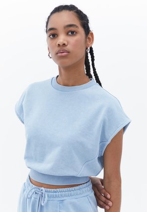 Light blue cropped sweatshirt with wide sleeves and ribbed collar. Soft texture, paired with matching sweatpants featuring an elastic waistband.