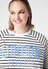 Gestreepte trui met navy en witte horizontale strepen, "LONDON" in lichtblauwe borduursels, en een ronde hals met raglanmouwen.