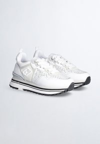 Scarpe sportive bianche con parte superiore in mesh e sintetico, dettagli perforati, accenti argento e suola in gomma nera con strisce bianche.