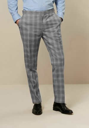 Grau karierte Hose mit schmalem Schnitt, mit flachem Bund und Seitentaschen. Tragen mit schwarzen Schuhen und einem hellblauen Hemd.