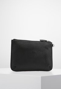 Pochette noire à fermeture éclair fabriquée en matériau synthétique, avec une texture lisse, un design minimaliste et des coins cousus pour plus de durabilité.