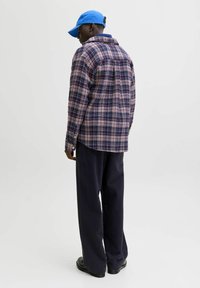 Tamsiai mėlynas, rožinis ir baltas languotas flanelinis marškinis su apykakle ir mygtukais. Dėvima su tamsiomis kelnėmis ir ryškiai mėlynu kepuraite. Lygios bateliai užbaigia įvaizdį.