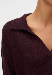 Maglione in bordeaux a maglia con colletto e finitura testurizzata, dotato di scollatura a V e morbido filato peloso.
