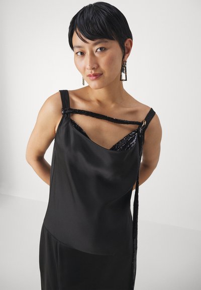 Rochie din satin negru cu un decolteu drapat și accente cu paiete. Are un singur bretele și un detaliu decorativ cu funda. Textură netedă în general.
