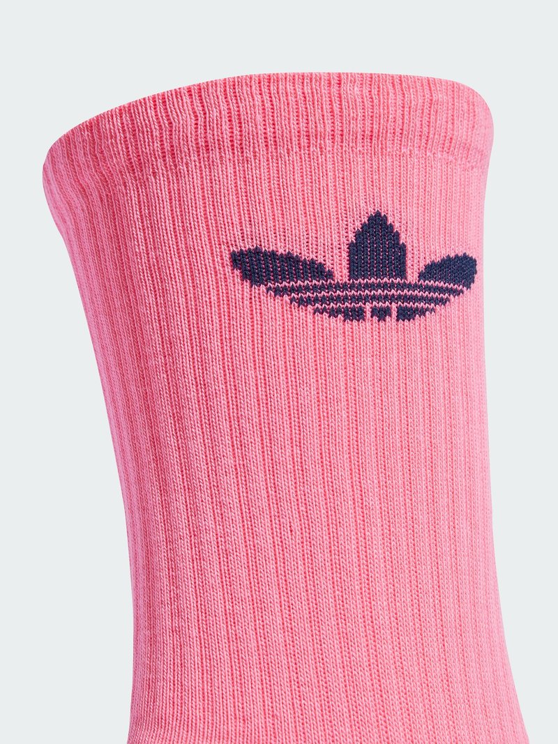 Calzino rosa a coste con un bordo più largo. Presenta un logo Adidas blu scuro sul lato. Il tessuto sembra morbido ed elastico con una texture liscia.