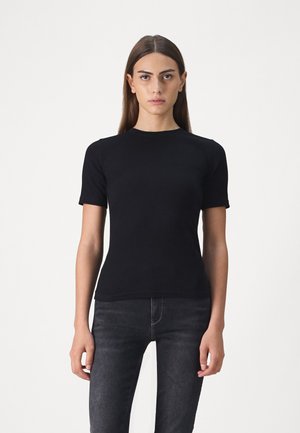 Svart kortermet t-skjorte laget av mykt stoff, med rund hals og en tettsittende design, sammen med mørke jeans.