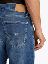 Blaue Jeans aus Denim mit einem Leder-Logo-Patch mit der Aufschrift "TOMMY JEANS" am Bund. Verfügt über sichtbare Nähte und ein standardmäßiges Design der Gesäßtasche.