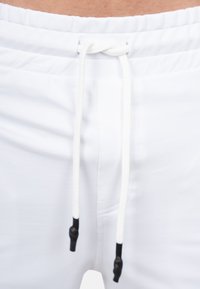 Witte zwembroek met een elastische tailleband, voorzien van een trekkoord met zwarte kunststof punten. Glad fabricus, zonder zichtbare patronen.