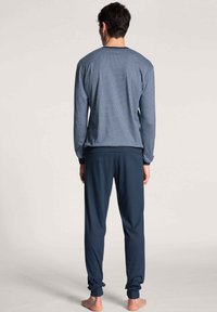 Navy blauwe pyjama set met een gestreepte lange mouwen top en effen kleurige broek, gemaakt van zachte, comfortabele stof met een relaxte pasvorm.