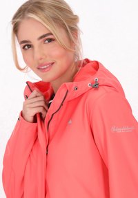 Koralinė vandeniui atspari striukė su kapišonu, užtrauktuku, reguliuojamu raišteliu ir sidabriniu logotipu. Lygi tekstūra ir prigludęs dizainas.