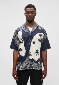 Μπλούζα κοντού μανικιού με ναυτικό φόντο και κρεμ λουλούδια και αστρονομικά μοτίβα; σχέδιο με κουμπιά και άνετη εφαρμογή.