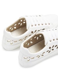 Weiße Sneakers mit durchbrochenem Blumenmuster, strukturiertem goldfarbenem Innensohle, weißen Schnürsenkeln und Gummisohle. Minimalistischer Stil mit Akzentdetails.