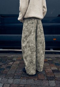 Szerokie, jasnoszare dżinsy z kwiatowym wzorem. Posiadają dwie tylne kieszenie, zestawione z puszystym swetrem w kolorze ecru oraz czarnymi butami.