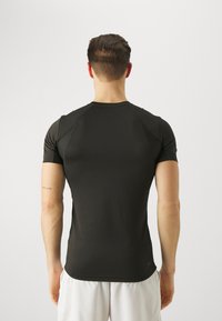 Camisa atlética negra de manga corta con un diseño ajustado, textura suave y mangas raglán, que cuenta con un escote redondeado y detalles de costura sutiles.