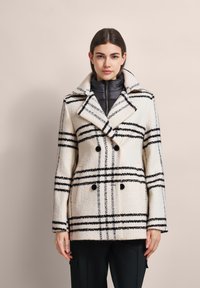 Doppelreihiger Mantel in Creme mit schwarzen und grauen Streifen, ausgestattet mit einem breiten Kragen, strukturiertem Stoff und zwei Knopfakzenten.