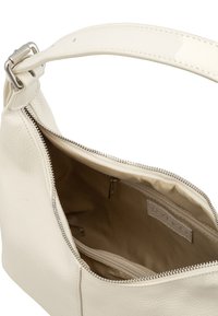 Kreemivärvi nahast käekott, millel on tõmblukk ja üks rihm. Sisemus on beeži voodriga ning sisaldab mitut taskut organiseerimiseks.