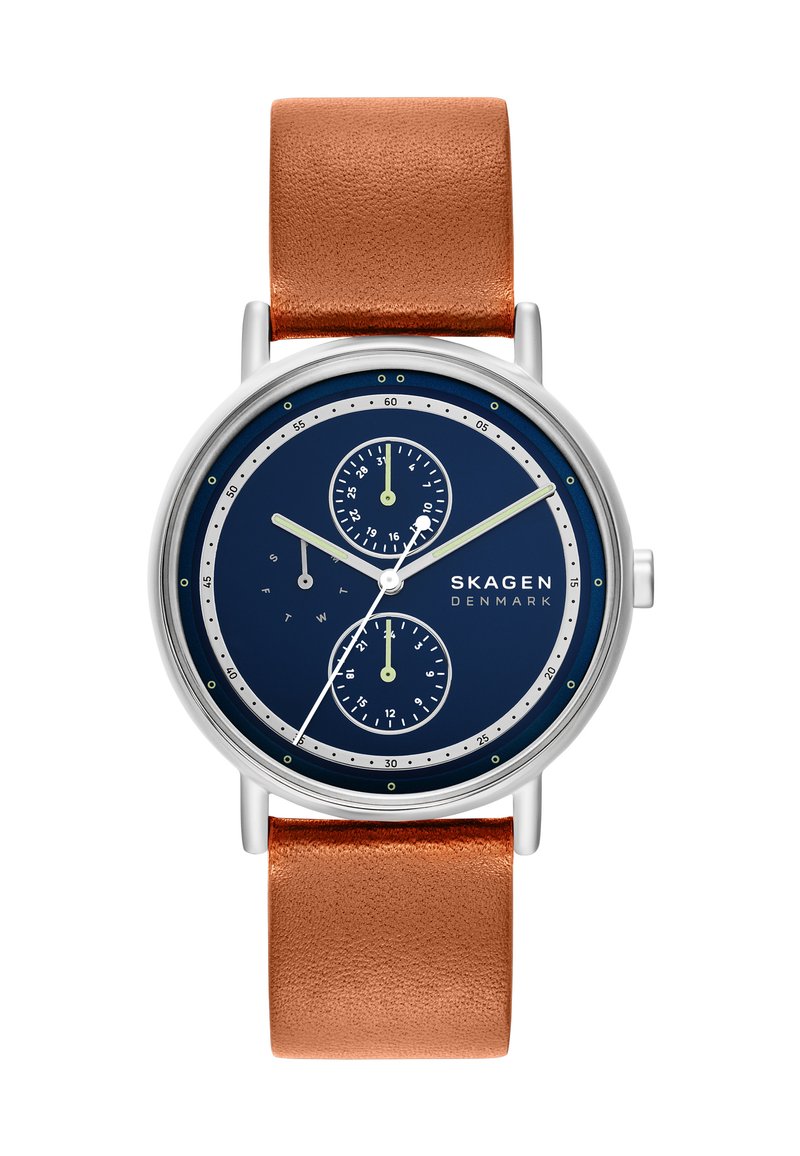 Montre Skagen avec un boîtier en acier inoxydable argenté, un cadran bleu marine, deux sous-cadrans et un bracelet en cuir marron avec une finition texturée.