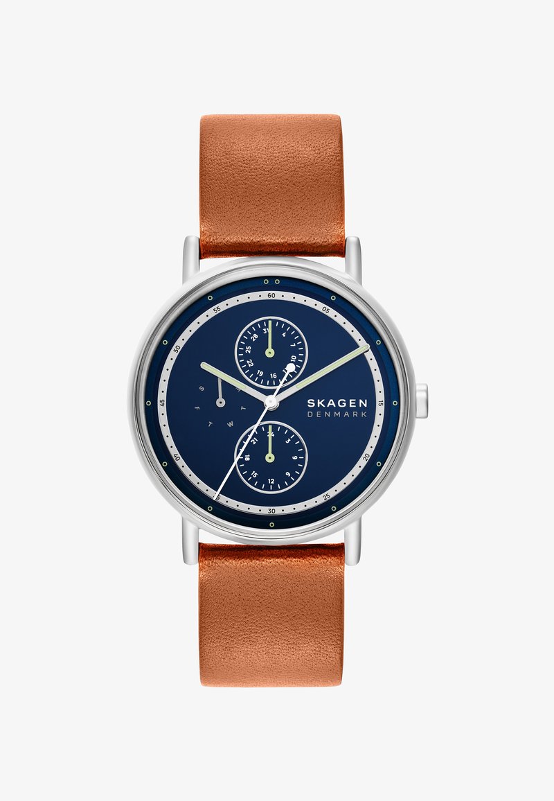 Relógio Skagen com caixa em aço inoxidável prateado, mostrador azul marinho, dois submostradores e uma correia em pele castanha com acabamento texturizado.