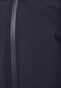 Navy sports jacket featuring a textured fabric, vertical glossy stripes, and a smooth zipper detail along the front.
