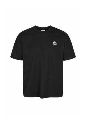 Mężczyzna w czarnej koszulce i dżinsach pokazujący tekst na plecach "Authentic Sportswear Brand Since 1967" z pięcioma gwiazdkami poniżej.