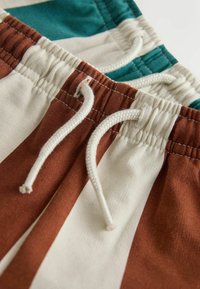 Färgglada badshorts med randigt mönster i mörkgrönt, krämvitt och rostfärgat, med elastisk midja och justerbar dragsko.